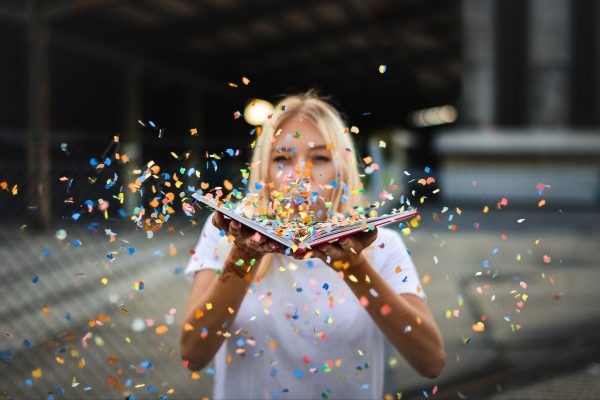 Une jeune fille tient un livre ouvert, ravie que la mise en page soit possible avec Correction En Ligne